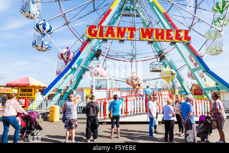 Urlauber beobachten ein Badeort Messegelände fahren. Menschen im Urlaub durch das riesige Rad am Pleasure Beach, Skegness, Lincolnshire, England, Großbritannien Stockfoto