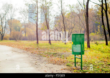 Neue grüne Papierkorb im Park im Herbst Stockfoto