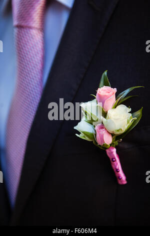 Boutonniere von rosa und weißen Rosenknospen am Revers seiner Jacke der Bräutigam ist schwarz Stockfoto