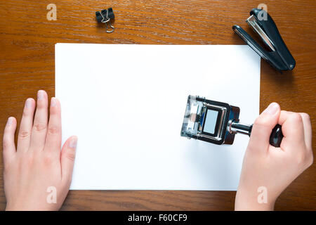 Hände ein Stempels auf das leere Blatt Papier Stockfoto