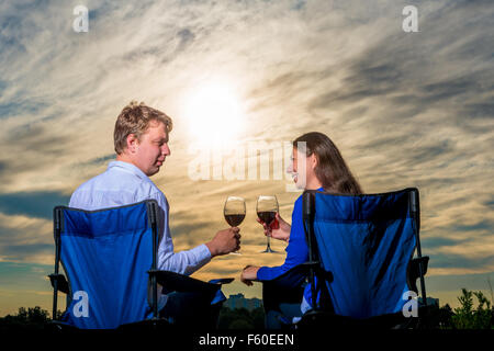 glückliche junge Ehepaar mit einem Glas Wein bei Sonnenuntergang Stockfoto