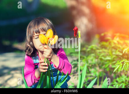 Kleines Mädchen schnüffeln Tulpe Blume im Garten Stockfoto
