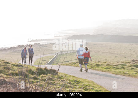 Paare auf Pfad, der von Mudeford Dorf an den Strandhütten am Mudeford, Christchurch Harbour, in der Nähe von Poole, Dorset, England geht, Stockfoto