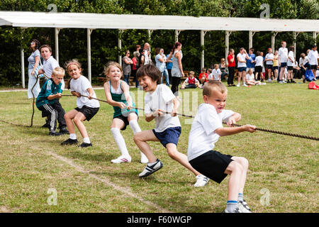 Kinder, 7-9 Jahre alt. Im Freien an einer Schule Sport Tag. Tauziehen Team, Füße gegraben, mit dem Team von g Kinder belasten Seil ziehen. Stockfoto