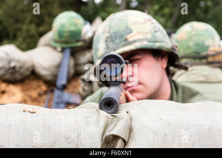 Vietnam Krieg Re-enactment-Gruppe. Amerikanische Soldaten, Scharfschützen, Kopf über Sandsäcke, die Zuschauer durch Umfang und Ziel. Close Up. Auge - Kontakt. Stockfoto