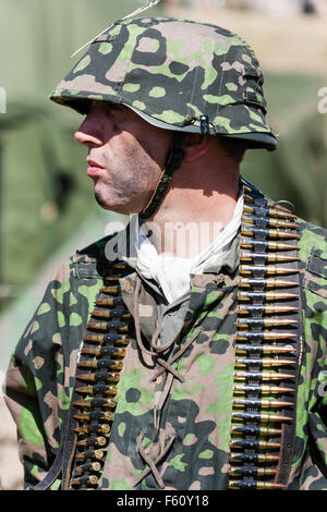 Zweiten Weltkrieg Re-enactment. Deutscher Soldat der Wehrmacht, in der Tarnung einheitliche, Kugeln um die Schultern hängen, mit Blick auf den Kopf drehte sich zu Seite. Stockfoto