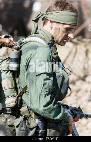 Vietnam Krieg Re-enactment, MACV-SOG Special Operations Soldat trägt bandana Stirnband mit Sturmgewehr in beiden Händen. Seitenansicht Stockfoto