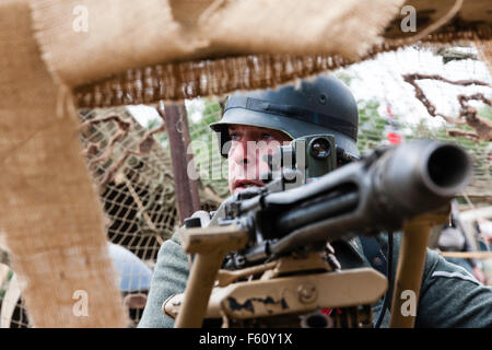 Zweiten Weltkrieg Re-enactment. Nahaufnahme von deutschen Soldaten Ziel mit schweren Maschinengewehr MG 42, in befestigten gegraben. Stockfoto