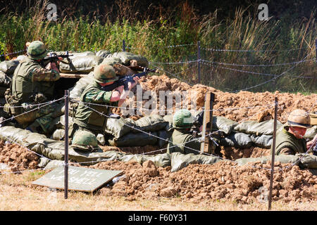 Vietnamkrieg 'Rolling Thunder' Re-enactment-Gruppe. Marines ducken in Graben schießen, zurück Brand während Scheingefecht. Von hinten gesehen. Stockfoto