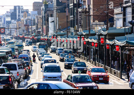 Japan, Kyoto, Gion. Blick entlang Shijo-Dori, belebten Hauptstraße, mit vier Bahnen eines Staus, Stores, überdachten Bürgersteig und rotem Papier Laternen. Tagsüber. Stockfoto