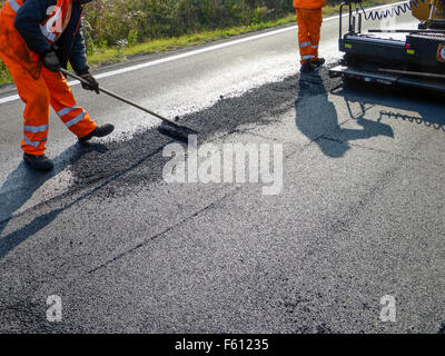 Arbeitnehmer verteilt Asphalt an einem heißen Sommertag Stockfoto