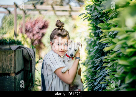 Mädchen und Hund kuscheln im Garten Stockfoto