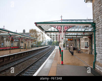 Guitarman warten auf die Plattform auf restauriert und unter Denkmalschutz stehenden Bahnhof in Grange-über-Sande Cumbria UK Stockfoto