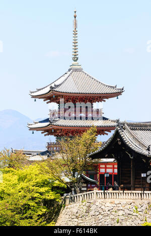 Japan, Kyoto. Kiyomizu dera Tempel. Die sanju - nein -, drei stöckigen vermilion Pagode hinter Bäumen und Gebäude. Mit einem blauen Himmel im Hintergrund. Stockfoto