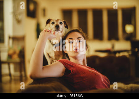 Jack Russell Terrier Hund sitzt auf der Rückseite eines Sofas mit seinem Besitzer sein Kinn kitzeln Stockfoto