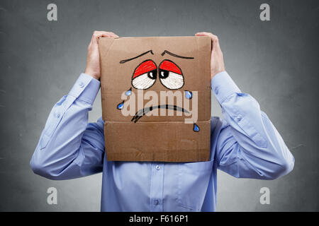Mann mit Karton auf dem Kopf zeigt traurigen Ausdruck Stockfoto