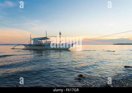 traditionelle Bangka Boot am philippinischen Strand bei Sonnenuntergang Stockfoto