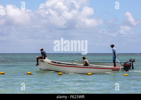 drei afrikanische Männer auf Boot mit Blick auf das Meer mit blauem Himmelshintergrund in Mauritius, Afrika Stockfoto