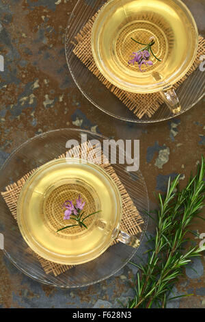 Frisch zubereitete Rosmarin Kräutertee in Tassen aus Glas, garniert mit Rosmarin-Blumen, fotografiert overhead auf Schiefer Stockfoto