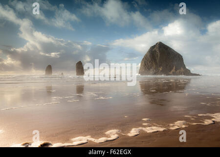 Dramatisches Licht und Himmel am Haystack Rock an der Küste Oregons. Haystack Rock ist ein 235-Fuß Meer Stapel in Cannon Beach, Oregon Stockfoto