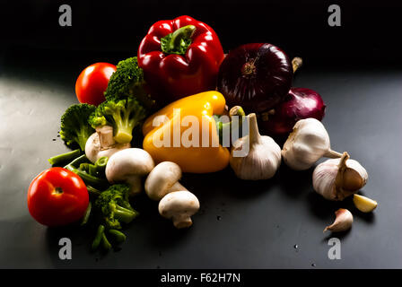 Still-Leben - Set Pizza auf schwarzem Hintergrund - Pilze, Champignons, Blumenkohl, Brokkoli, grüne Bohnen, Knoblauch Stockfoto