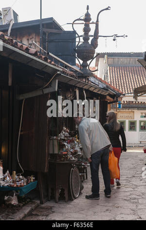 Touristen flanieren Pass Coffepots und andere Artikel für den Verkauf in Bascarsija – Sarajevos alten Basar. Stockfoto