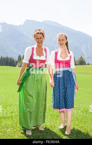 Zwei Freundinnen im Dirndl gehen auf Wiese spazieren Stockfoto