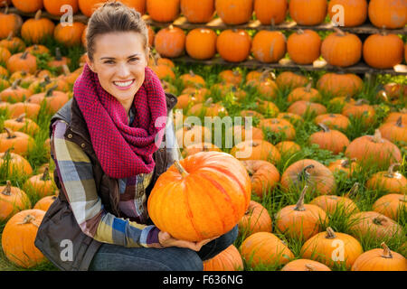 Porträt der lächelnde Frau sitzen und halten großen Kürbis auf Hof während der Herbstsaison Stockfoto