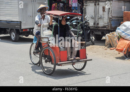 Eine Fahrradrikscha trägt eine Frau in Makassar, Indonesien Stockfoto