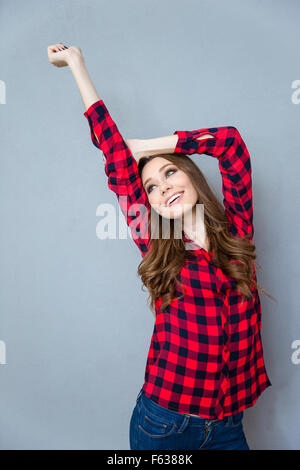 Hübsche junge lockig Frau im karierten Hemd, stretching und lächelnd Stockfoto