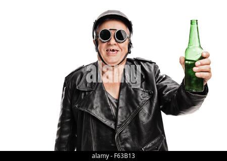 Zahnlose senior Motorradfahrer in schwarzem Lederjacke und Schutzbrillen hält eine Flasche Bier und schaut in die Kamera Stockfoto