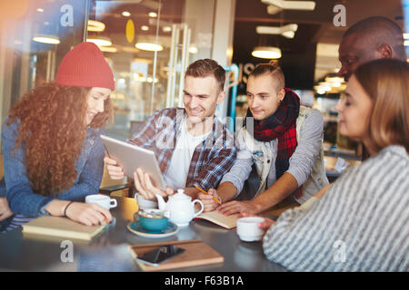 Gruppe von modernen Teenager Freunden mit Touchpad sitzen im café Stockfoto