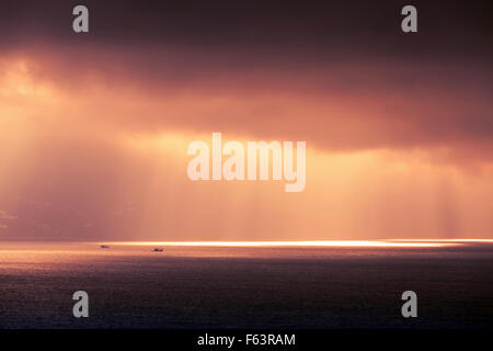 Atlantischen Ozean Landschaft Abend Sonne durchläuft dunkel bewölkter Himmel. Lila rot Tonwertkorrektur-Foto-Filter-Effekt Stockfoto