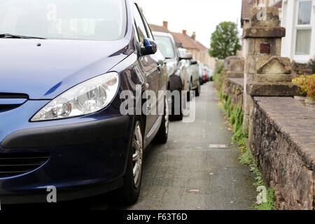 Eine Reihe von Autos auf dem Fußweg/Pflaster lassen wenig Raum für Fußgänger geparkt. Alle haben die Aufkantung außerhalb ihrer Häuser auf einem viktorianischen ter montiert Stockfoto