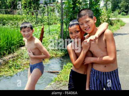 Jiu-Chi-Town, China: Drei chinesischen Jungen in ihren Badeanzügen an einem kleinen Bach, wo sie an einem Sommernachmittag schwimmen Stockfoto