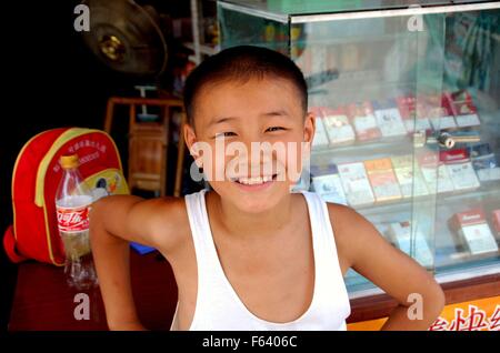 Jiu-Chi-Town, China: Lächelnd kleinen chinesischen Jungen vor ein kleines Lebensmittelgeschäft verkaufen Zigaretten Stockfoto