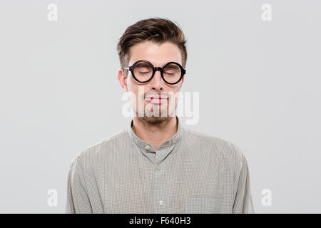Junge schöne lustige amüsante Kerl in graues Shirt mit geschlossenen Augen in schwarz Runde Brille Stockfoto