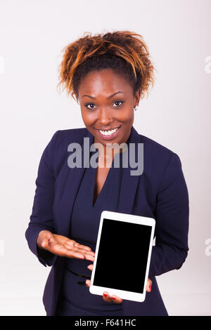 Afrikanische amerikanische Geschäftsfrau zeigt eine taktile Tablet, auf grauem Hintergrund isoliert Stockfoto