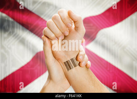 Barcode-ID Nummer Tattoo am Handgelenk und USA Staaten Flagge auf Hintergrund - Alabama Stockfoto