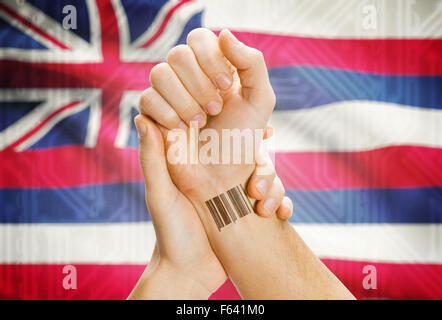 Barcode-ID Nummer Tatoo am Handgelenk und USA Statesl Flagge auf Hintergrund - Hawaii Stockfoto