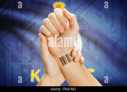 Barcode-ID Nummer Tatoo am Handgelenk und USA Statesl Flagge auf Hintergrund - Kansas Stockfoto