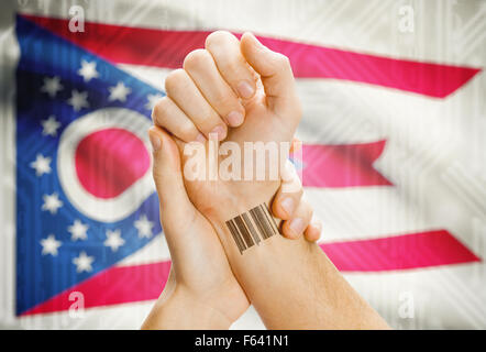 Barcode-ID Nummer Tatoo am Handgelenk und USA Statesl Flagge auf Hintergrund - Ohio Stockfoto