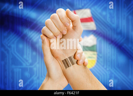 Barcode-ID Nummer Tatoo am Handgelenk und kanadischen Provinz Flagge auf Hintergrund - Alberta Stockfoto