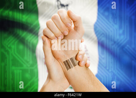 Barcode-ID Nummer Tatoo am Handgelenk und kanadischen Provinz Flagge auf Hintergrund - Yukon Stockfoto