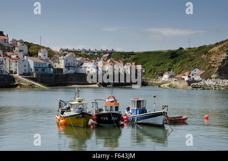 Sonnigen Sommertag mit blauem Himmel festgemacht 3 bunten Fischerbooten im Hafen mit dem malerischen Dorf Staithes, North Yorkshire, UK, darüber hinaus. Stockfoto