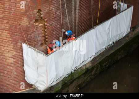 London, UK. 11. November 2015.  Bauarbeiter bei Arbeiten auf einem Backstein unterstützt unter Hungerford Bridge.  Sie stehen auf einer speziell schwebenden Plattform mit der Themse ein paar Füße darunter und Schienen in Charing Cross Bahnhof über ihnen. Bildnachweis: Stephen Chung / Alamy Live News Stockfoto