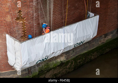 London, UK. 11. November 2015.  Bauarbeiter bei Arbeiten auf einem Backstein unterstützt unter Hungerford Bridge.  Sie stehen auf einer speziell schwebenden Plattform mit der Themse ein paar Füße darunter und Schienen in Charing Cross Bahnhof über ihnen. Bildnachweis: Stephen Chung / Alamy Live News Stockfoto