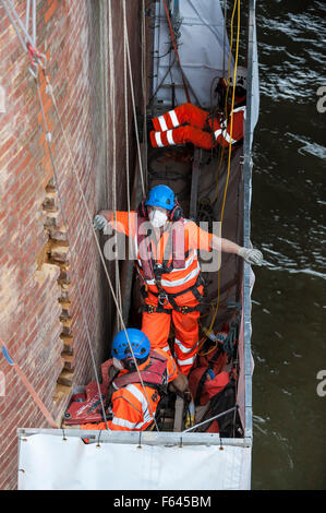 London, UK. 11. November 2015.  Bauarbeiter bei Arbeiten auf einem Backstein unterstützt unter Hungerford Bridge.  Sie stehen auf einer speziell schwebenden Plattform mit der Themse ein paar Füße darunter und Schienen in Charing Cross Bahnhof über ihnen. Bildnachweis: Stephen Chung / Alamy Live News Stockfoto