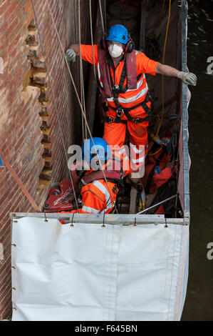 London, UK. 11. November 2015.  Bauarbeiter bei Arbeiten auf einem Backstein unterstützt unter Hungerford Bridge.  Sie stehen auf einer speziell schwebenden Plattform mit der Themse ein paar Füße darunter und Schienen in Charing Cross Bahnhof über ihnen. Bildnachweis: Stephen Chung / Alamy Live News Stockfoto