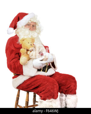 Weihnachtsmann sitzt auf einem Stuhl halten Teddybären für Weihnachten Stockfoto